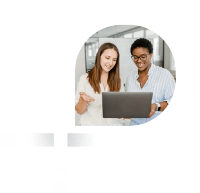 Duas mulheres sorridentes, uma de cabelos castanhos e outra de cabelos curtos escuros e óculos, trabalham juntas em um notebook em um ambiente de escritório. A imagem transmite colaboração e produtividade. Duas mulheres sorridentes, uma de cabelos castanhos e outra de cabelos curtos escuros e óculos, trabalham juntas em um notebook em um ambiente de escritório. A imagem transmite colaboração e produtividade.